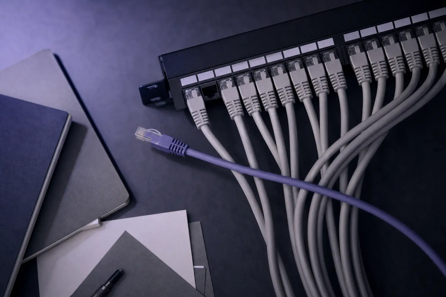 Patchfeld mit Netzwerkkabeln, ein Kabel liegt ausgesteckt quer darueber